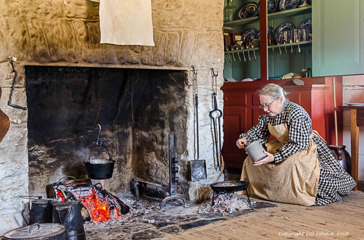 Picture of a woman cooking over a fire in the 1850s house